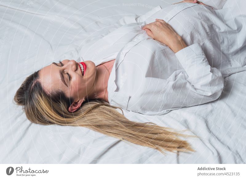 Positive schwangere Frau mit Hand auf dem Bauch auf dem Bett liegend Angebot sanft mütterlich Harmonie positiv vorwegnehmen erwarten Schwangerschaft Lächeln