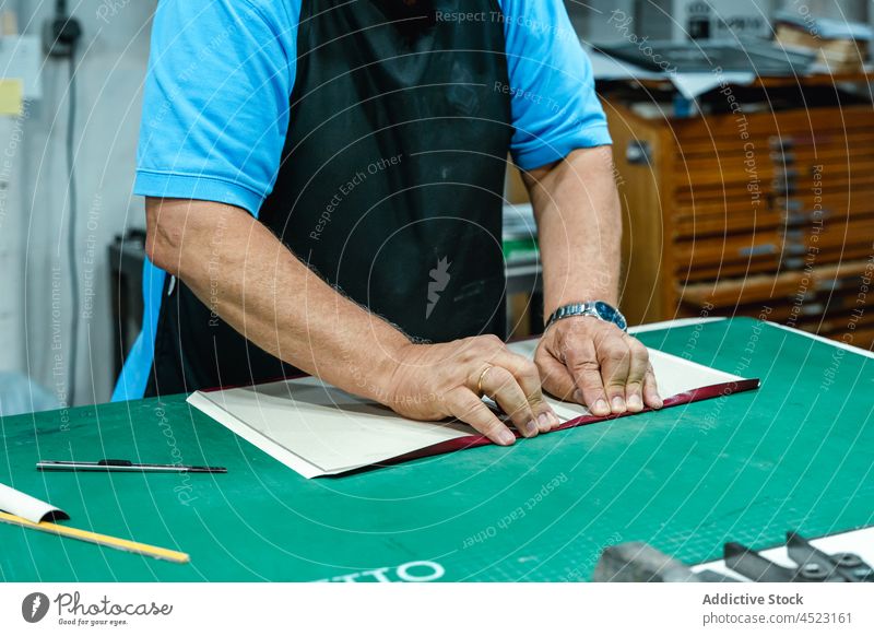 Kunsthandwerker beim Falten von Buchdeckeln in der Druckerei Mann Pferch Deckung Arbeit Kunstgewerbler Handwerk Werkstatt drucken kreieren Beruf Basteln
