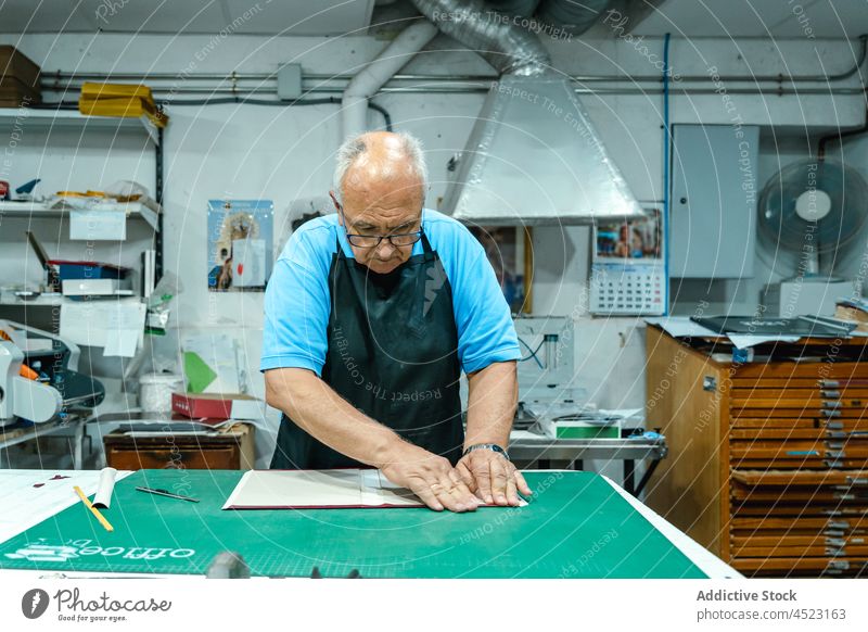 Kunsthandwerker beim Falten von Buchdeckeln in der Druckerei Mann Pferch Deckung Arbeit Kunstgewerbler Handwerk Werkstatt drucken kreieren Beruf Basteln