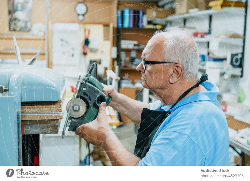 Fokussierter älterer männlicher Meister bei der Arbeit mit einer Kreissäge in einer Werkstatt Mann benutzend kreisrund Säge Holzarbeiten Zimmerer Konzentration