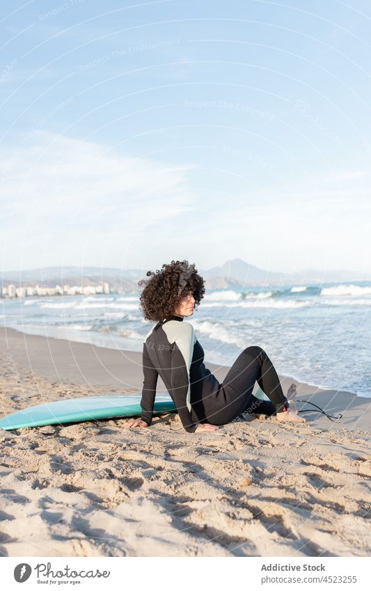 Frau im Neoprenanzug mit Surfbrett am Sandstrand liegend Surfer Strand MEER winken Meereslandschaft Harmonie tropisch Ufer Küste sich[Akk] entspannen exotisch