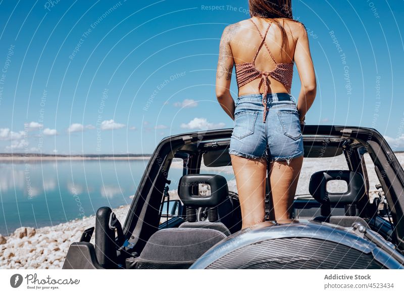 Anonyme trendige Dame steht im Cabrio und bewundert das Meer Frau bewundern Meereslandschaft PKW Autoreise Reisender Strand Urlaub MEER Natur Ausflug jung