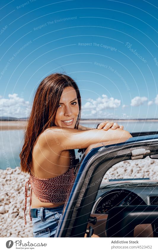 Junge Frau lehnt sich aus dem Auto sich[Akk] entspannen Teich sorgenfrei Fenster PKW Freiheit Ufer Kälte Natur Küste Verkehr Fluss Reisender Jeansstoff