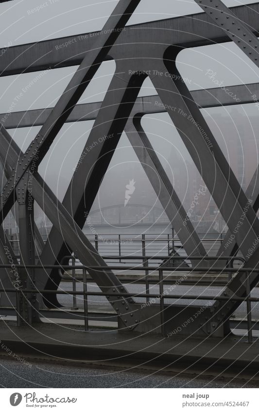 Blick durch die Eisenstreben einer Hafenbrücke auf weitere Brücken im nebligen Hintergrund Hamburg Eisenkonstruktion Struktur Vintage Industrie Verkehrswege