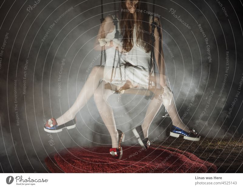 Ein Doppelbelichtungsbild eines jungen brünetten Mädchens in einem sexy weißen Kleid. Ihre schicken, glänzenden Schuhe ziehen ebenfalls die Aufmerksamkeit auf sich. Eine Art Rauch oder Nebel im Bild schafft eine stimmungsvolle Atmosphäre.