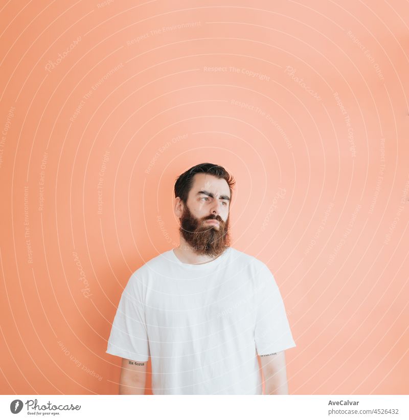 Junge Hipster bärtigen Mann Blick weg von der Kamera, Kopie Raum, weiche orange abnehmbarem Hintergrund, minimal basic, Ad-Konzept Deal, weißes Hemd Raum