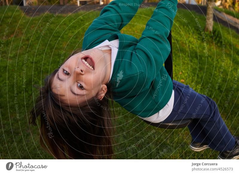 Overhead-Aufnahme eines fünfjährigen Mädchens in einer Schuluniform, das an einem Seil hängt Spielplatz Fliege Reiten Spaziergang Kind niedlich im Freien Glück