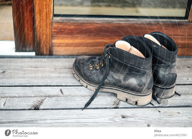 Staubige Wanderstiefel vor der Terassentür Wanderschuhe staubig Schuhe schwarz Leder Stiefel Holz Schuhpaar dreckig wandern Outdoor Lederschuhe