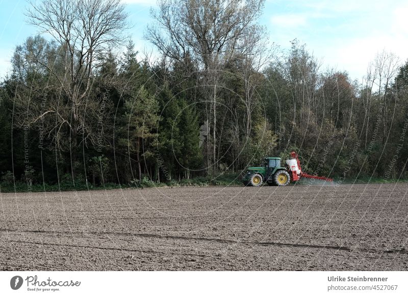 Bauer bringt mit seinem Traktor Dünger auf dem herbstlichen Feld aus Landwirtschaft Ackerbau Umwelt Wiese Maschine Erde Wald düngen ländlich Trecker