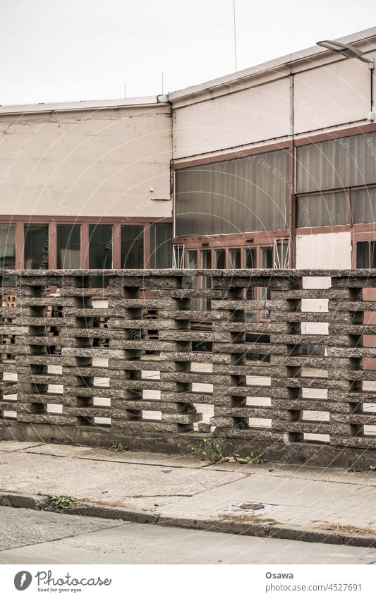 Gewerbe hinter Einfriedung Betrieb Firma Firmengelände Zaun Mauer Beton Stadt grau versiegelt Fassade alt monochrom Gebäude Menschenleer Außenaufnahme trist