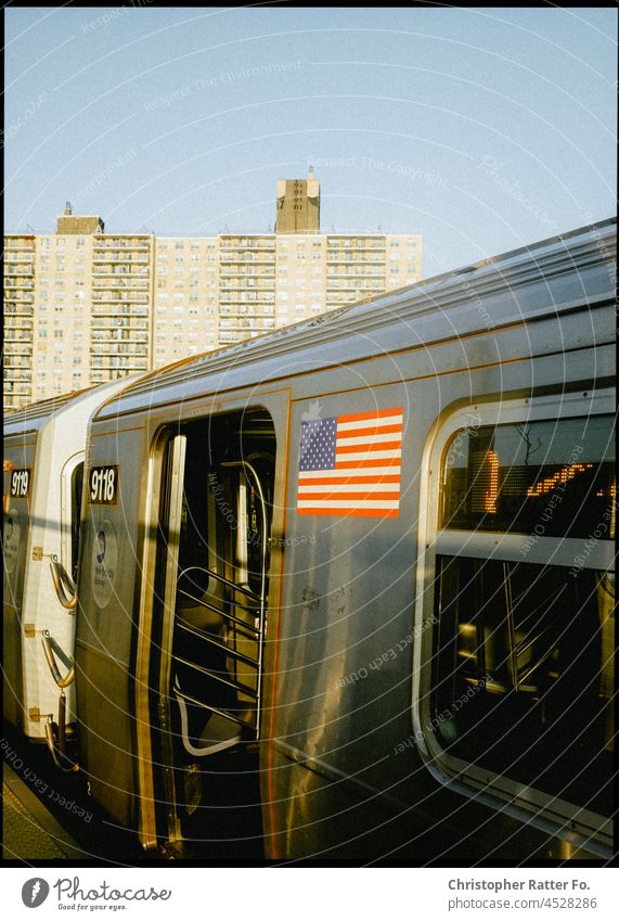Stommungsvoller Blick auf eine New Yoker U-Bahn mit US-Flagge nahe Conny Island. Brooklyn, New York. Filmlook Tourismus Dämmerung Licht warm Bundestagswahlen