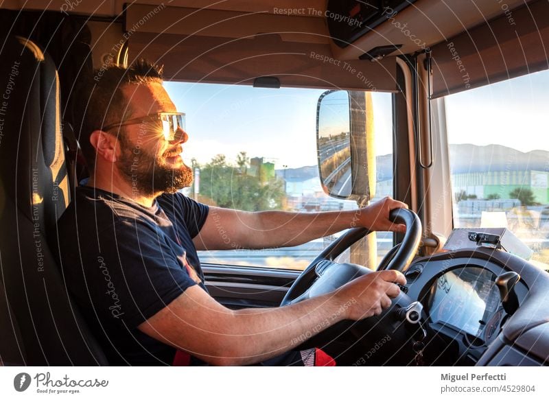 Lkw-Fahrer, der mit beiden Händen das Lenkrad hält und die Sonne nach vorne richtet. Lastwagen arbeiten Glück Sonnenuntergang fahren Verkehr Männer glückselig