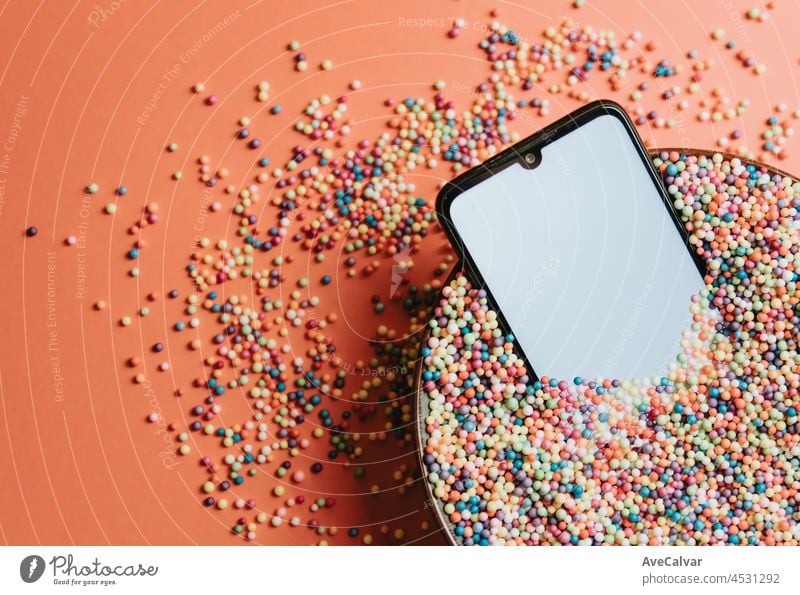Fancy bunten Bild eines Mobiltelefons in einer Schüssel mit bunten Kugeln mit leeren Bildschirm mit Kopie Raum, Kind Bild, Partei soziales Netzwerk-Stil
