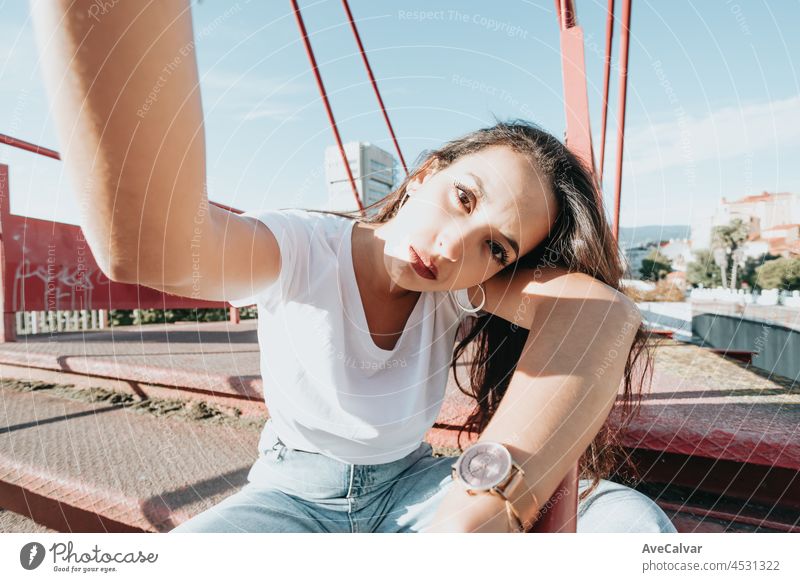 Junge städtische gemischtrassige Frau, die ein Selfie macht, während sie ernst in die Kamera schaut, städtischer Lebensstil, weißes T-Shirt leerer Raum, trendiges soziales Netzwerk, junge Leute, Weitwinkelaufnahme