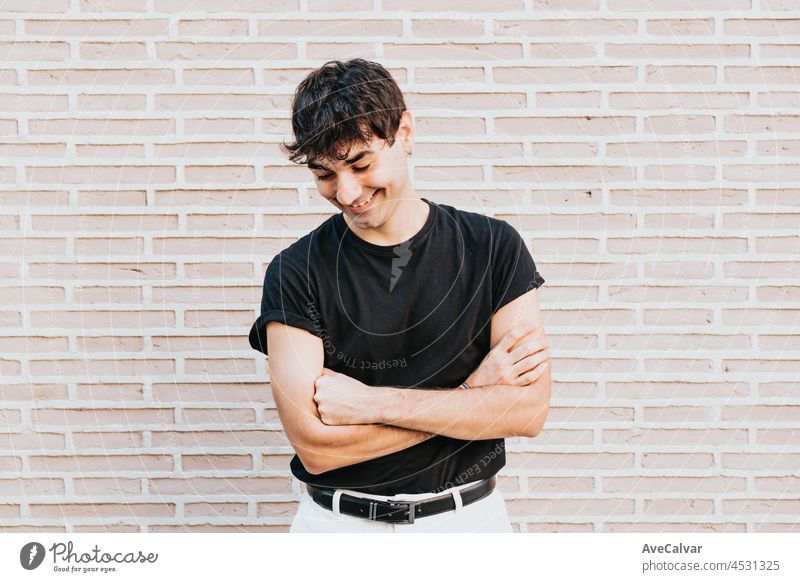 Junger urbaner Mann mit schwarzem T-Shirt, lachend, während er porträtiert wird, selbstbewusst und glücklich, neuer Bewerber, der Zukunft mit Freude entgegenblickend, Kopierraum, lgbt