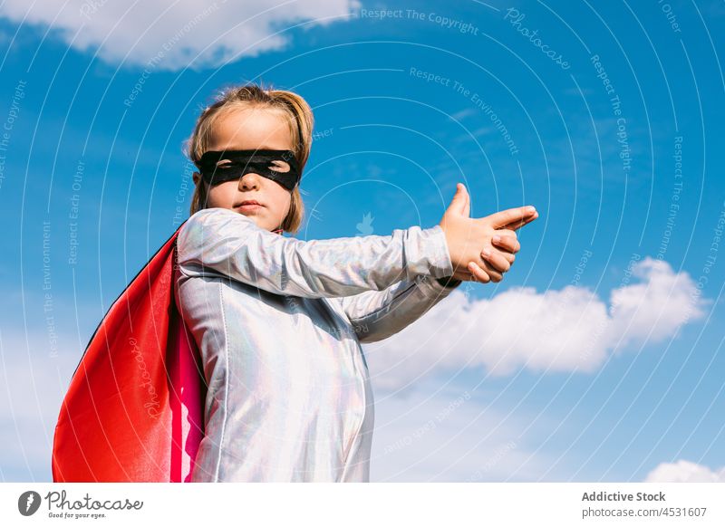 Furchtloses Mädchen im Superheldenkostüm zeigt Schussgesten Mut selbstbewusst gestikulieren so tun, als ob schießen behüten Tracht Kind Mundschutz retten zeigen