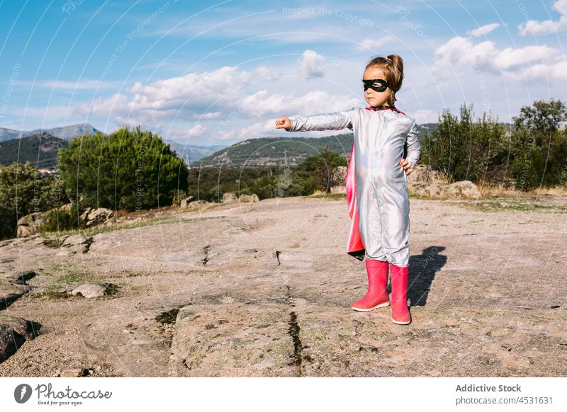 Tapferes Kind im Superheldenkostüm zeigt Fäuste Mädchen stark Kraft Faust Mut so tun, als ob furchtlos gestikulieren Hügel Kap Tracht Kindheit Stärke behüten