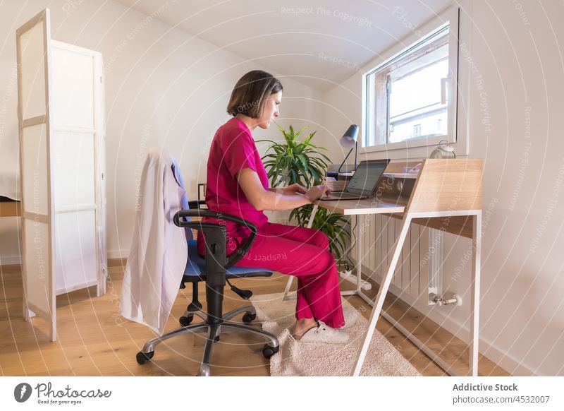 Frau in Uniform arbeitet am Laptop im Büro einer Kosmetikerin Kosmetologe Tippen benutzend Medizin beschäftigt Job Arbeitsplatz Kosmetologie online Internet