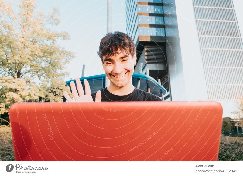 Porträt eines jungen Business-Student Kerl in einem schwarzen Hemd mit dem Laptop tun einen Videoanruf in einem Outdoor, Notebook Student Business-Konzept, modernes Design Business-Gebäude