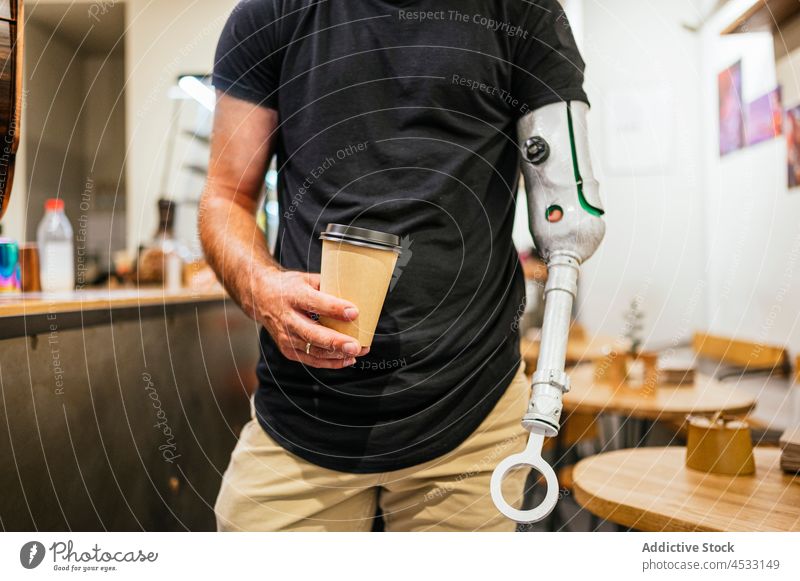 Mann mit Beinprothese und einer Tasse Kaffee Prothesen Bionik Arme Café Amputierte künstlich Glied männlich Imbissbude Handicap Getränk Pappbecher trinken