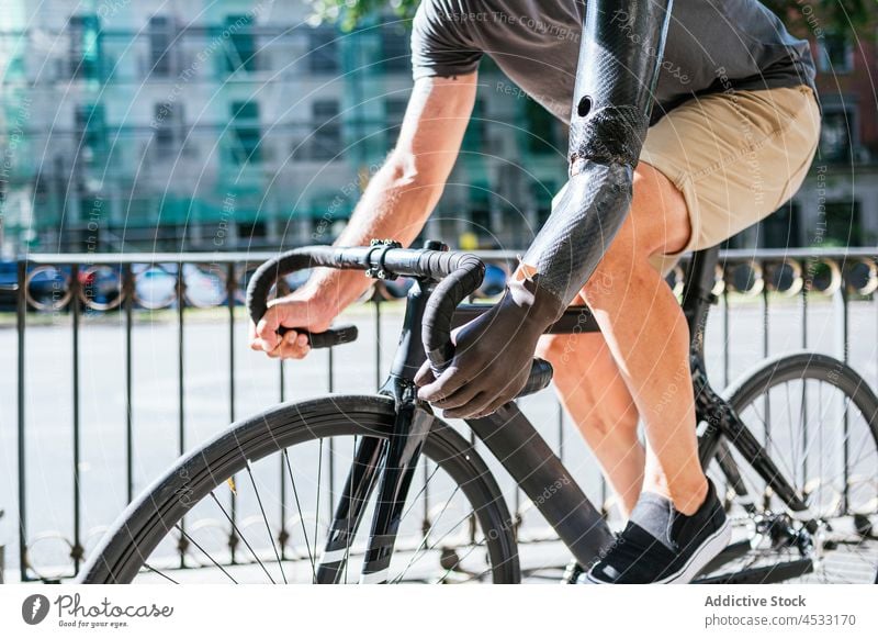 Anonymer Mann mit bionischem Arm fährt Fahrrad in der Stadt künstlich Arme Prothesen Handicap Prothetik Mitfahrgelegenheit Großstadt Bionik männlich Straße