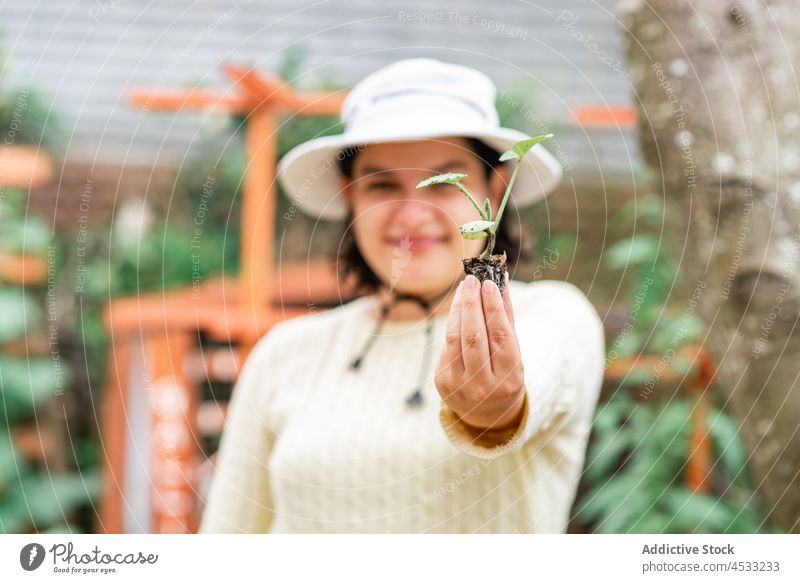Lächelnde Frau zeigt Sprössling im Garten Gärtner Aussaat sprießen Vorbau zeigen Pflanze Ackerbau kultivieren positiv Bauernhof Botanik wachsen Arbeit