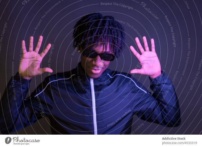 Stilvoller schwarzer Mann zeigt Handflächen in dunklem Studio cool modern ernst Körperhaltung Persönlichkeit Vorschein selbstbewusst trendy männlich