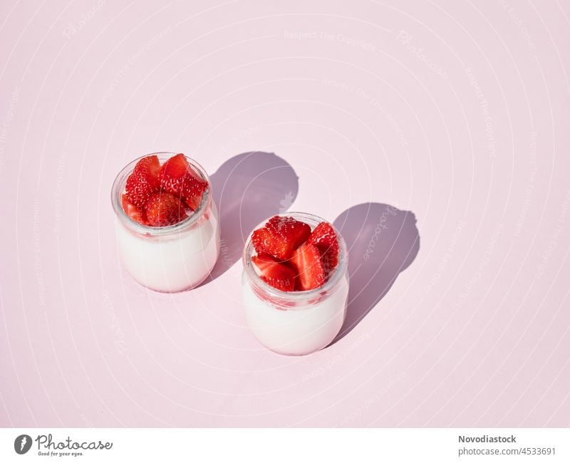 zwei Gläser mit Naturjoghurt und frischen Erdbeeren isoliert auf hellrosa Hintergrund, mit Copy Space Joghurt natürlich erdbeeren melken Frucht vereinzelt