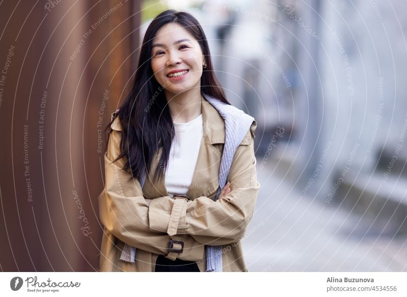 Schöne Business asiatische Frau mit brünetten Haaren tragen lässig Trenchcoat im Herbst im Freien Glück Lächeln schön Mode Porträt Mädchen Lifestyle attraktiv