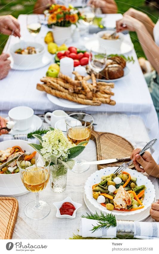 Familienfeiern und Lebensmittelkonzept. Die Familie isst bei einem Sommergartenfest zu Abend. Gedeckter Tisch und Dekoration. Speisen und Getränke. Gegrilltes, Gemüse, Wein und andere Snacks. Das Leben in den Vorstädten