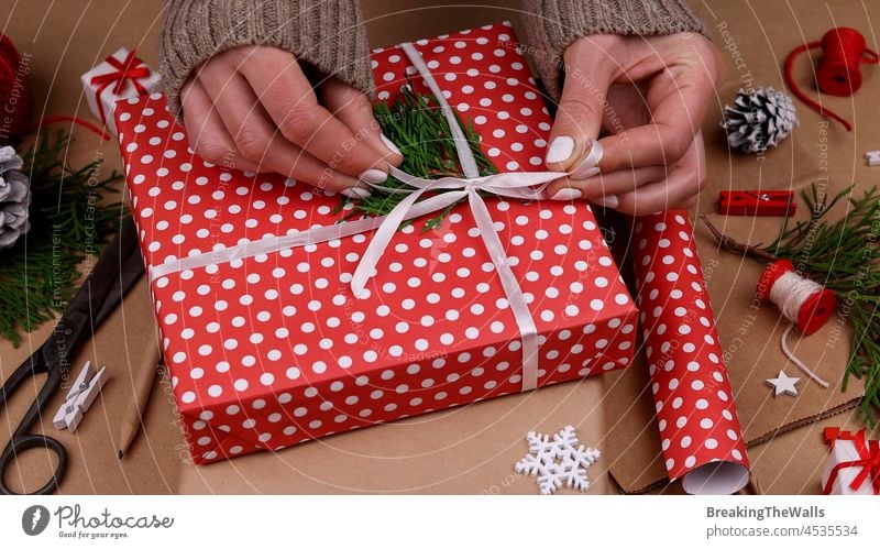 Frau verpackt Weihnachtsgeschenke mit rotem Papier Geschenk Rudel braun braunes Papier Geschenkbox Kasten umhüllen Hände weiß Kaukasier natürlich Weihnachten