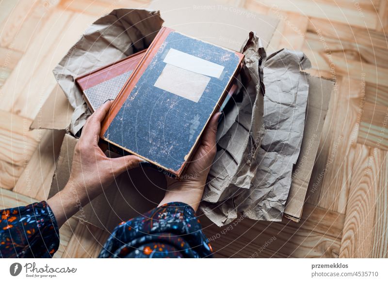 Frau, die Bücher aus einer Kiste nimmt. Auspacken des Pakets herausnehmend Buch Kollo Karton Kasten Spedition offen Klient neu Versand senden Gewerbe Kurier