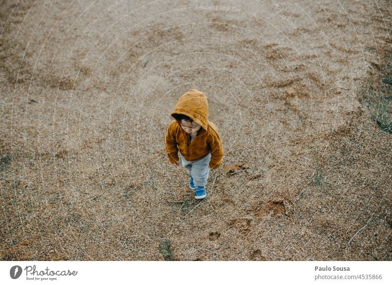 Kind mit orangefarbenem Kapuzenpulli unterwegs Kindheit Kaukasier 1-3 Jahre authentisch Herbst Kapuzenpullover Natur Pullover Außenaufnahme Mensch Farbfoto Tag