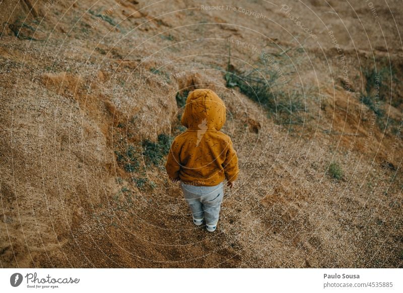 Rückansicht Kind mit orangefarbenem Kapuzenpulli 1-3 Jahre erkunden Farbfoto Außenaufnahme Natur Spielen authentisch Freude Kindheit Kaukasier Leben