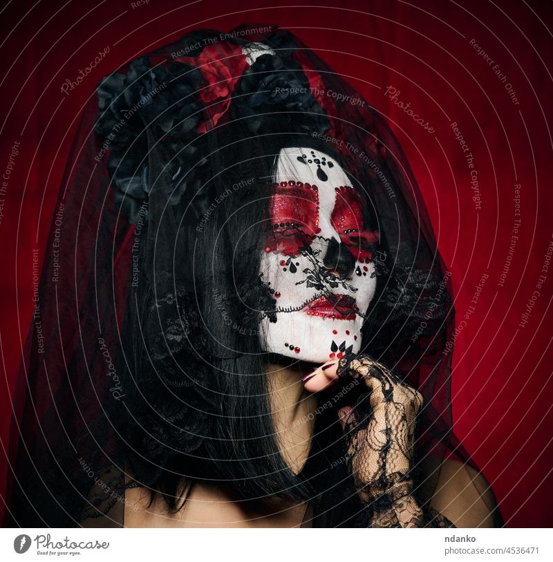 schöne Frau mit einem Zuckerschädel Make-up mit einem Kranz von Blumen auf dem Kopf, roter Hintergrund Halloween Schädel Entsetzen Schönheit Porträt Tracht Tod