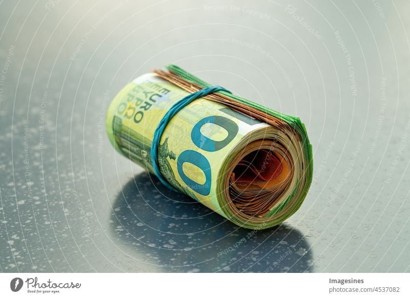 Euro Geldrolle auf einem dunklen Tisch. 100- und 50-Euro-Scheine zu einer rolle gedreht und mit einem Gummiband zusammengebunden. Aufgerollte Euro-Scheine