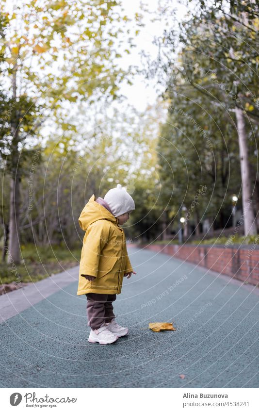 Cute kaukasischen Baby Mädchen ein Jahr alt zu Fuß im Herbst im Freien. Glückliches gesundes Kind mit Smiley-Gesicht genießt das Leben und Herbst Saison auf Sonnenuntergang