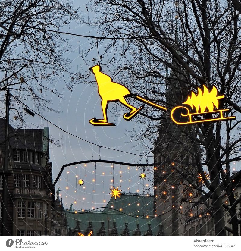 Winterbeleuchtung Schlittschuhläufer mit Schlitten und Tannenbaum schwebt über der Einkaufsstraße in Hamburg vor dem Rathaus leuchten Advent Weihnachten