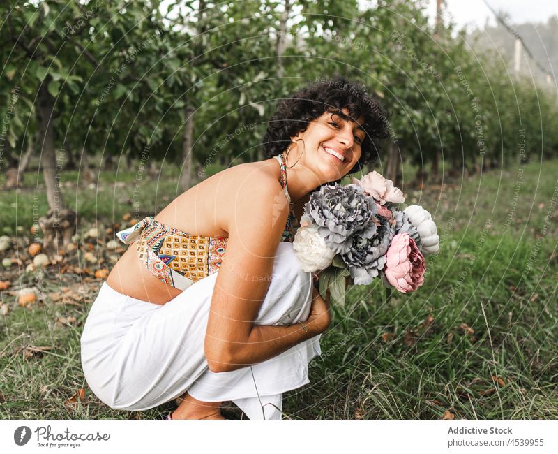 Glückliche Frau mit Blumenstrauß, die ihre Knie im Garten umarmt Pfingstrose üppig (Wuchs) Blütezeit charmant sanft Knie umarmend Haufen Inhalt Pflanze Frucht