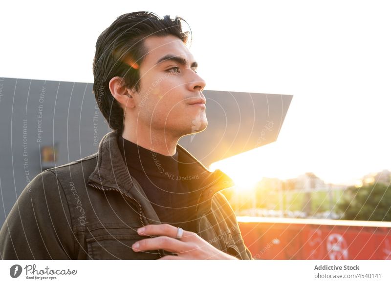 Seriöser asiatischer Mann auf sonniger Straße Gebäude Großstadt Stil urban modern Vorschein Sonnenlicht Outfit ethnisch Bekleidung trendy Typ männlich