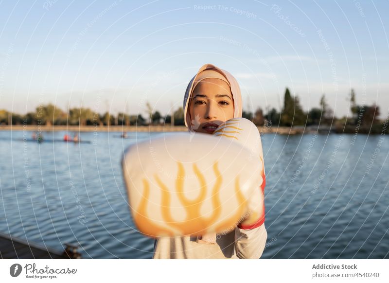 Sportliche arabische Frau beim Boxen am Wasser Stauanlage Boxsport Fluss Bowle üben Training Gesunder Lebensstil Handschuh Übung muslimisch Kasten Hafengebiet
