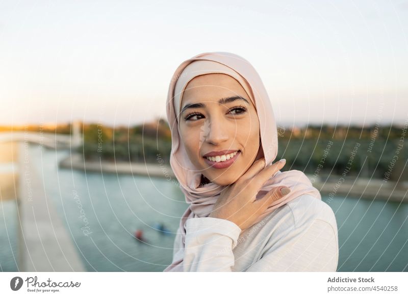 Porträt einer fröhlichen arabischen Frau an der Uferpromenade Hafengebiet Stauanlage Hijab Fluss Wasser Freizeit Zeitvertreib Flussufer Reling Barriere Durst