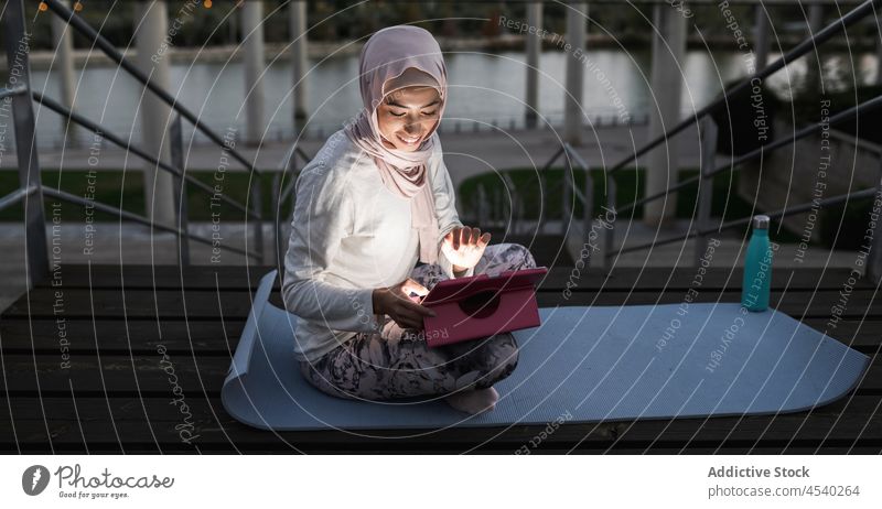Arabische Frau beim abendlichen Surfen auf einem Tablet am Ufer Tablette Abend Treppe Browsen online Hafengebiet Stauanlage Hijab Fluss Wasser Freizeit