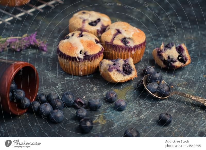 Leckere gebackene Heidelbeermuffins mit Sahne auf dem Tisch Muffin Blaubeeren selbstgemacht süß Zusammensetzung Dessert Leckerbissen lecker Lebensmittel Löffel