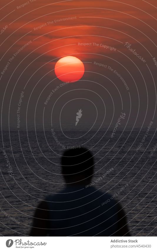 Silhouette eines anonymen Reisenden, der den Sonnenuntergang am Meeresufer genießt Mann bewundern Tourist Urlaub Meereslandschaft MEER malerisch Reisender