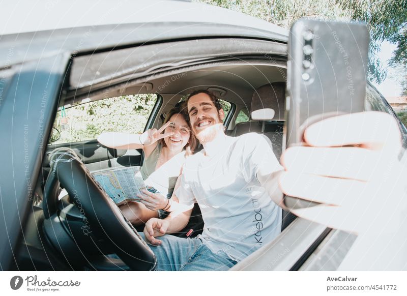 Schönes junges Paar, das eine Autoreise unternimmt. Autoreise, Frontalporträt lächelnd. Sie machen eine Pause vom Fahren und nehmen ein Selfie mit ihrem Telefon. Hipster modernes Paar.
