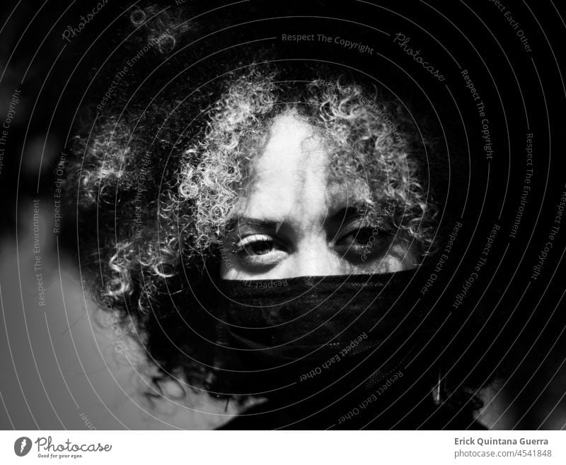 Porträt einer Frau mit Maske Schwarzweißfoto schwarz auf weiß Schwarz-Weiß-Fotografie Afrohaar krause Haare Kräusel große Augen Frauenporträt