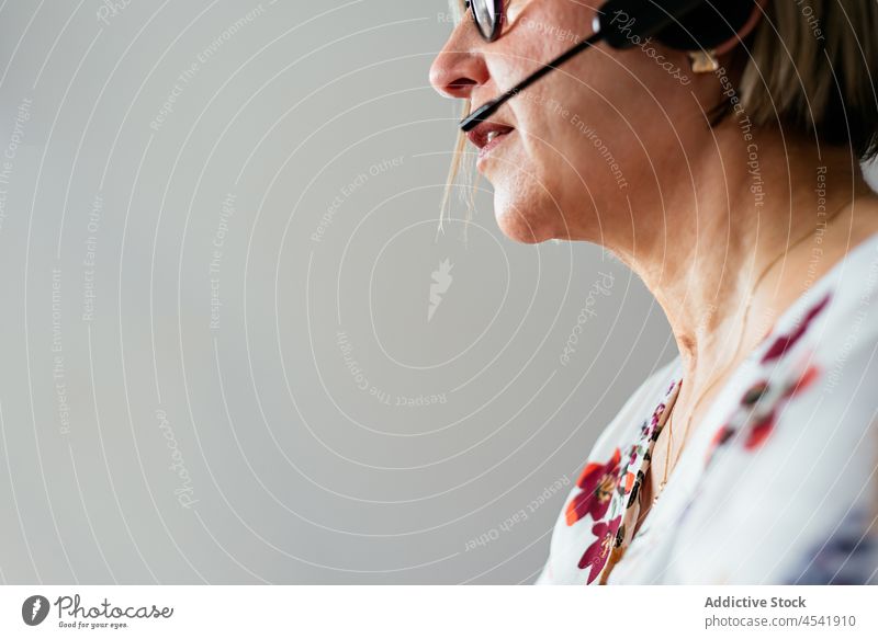 Anonyme reife Frau mit Brille und Headset Telearbeit Betreiber benutzend online Internet Arbeit Apparatur Konzentration beschäftigt Entfernung ernst unabhängig
