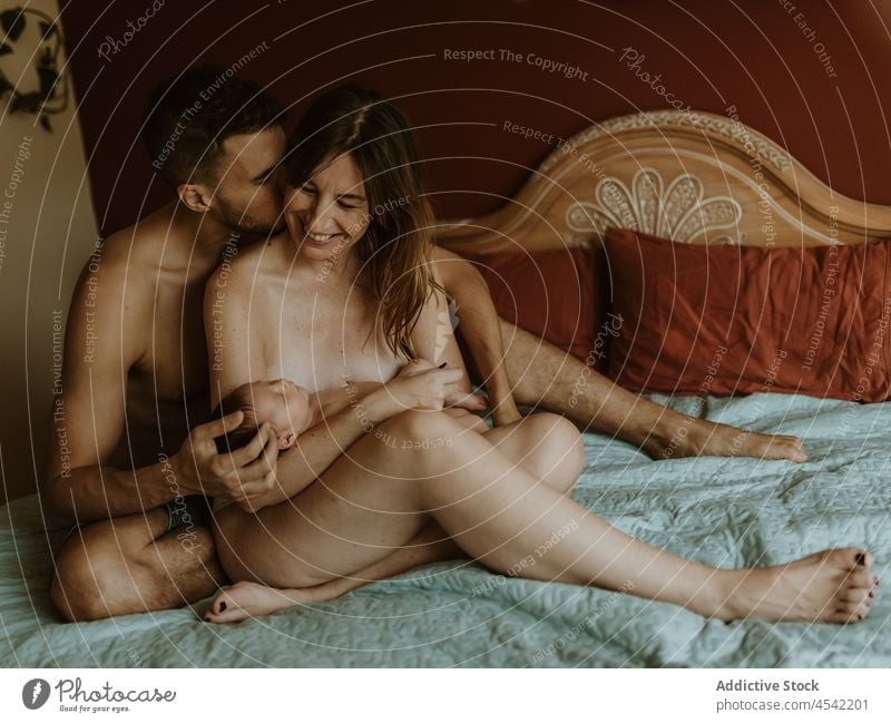 Glückliches nacktes Paar mit Baby kuschelnd auf dem Bett Familie neugeboren Kuss stillen Liebe Zusammensein Umarmen Partnerschaft schließen Ehefrau Ehemann