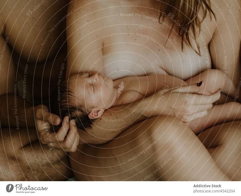 Anonymes nacktes Paar mit Baby kuschelnd auf dem Bett Familie neugeboren stillen Liebe Zusammensein Umarmen Partnerschaft schließen Ehefrau Ehemann Erwachsener